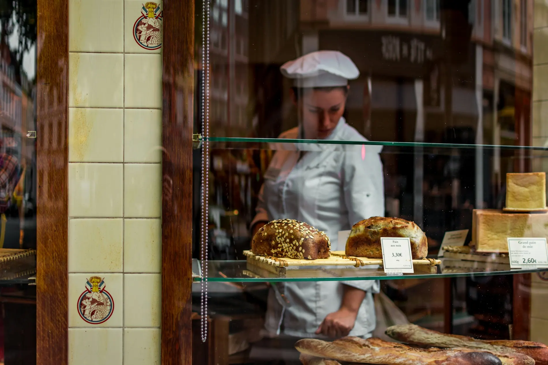 Bäcker hinter der Glastheke seiner Bäckerei