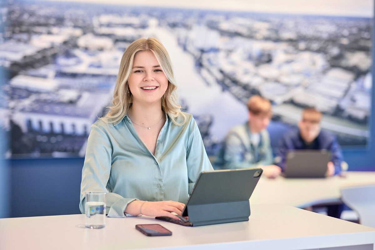 Mitarbeiterin am Schreibtisch mit Tablet in modernem Büro